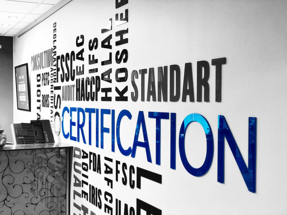 Стена в офисе Easy Standart с названиями стандартов и схем сертификации
